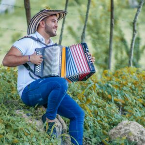 A Colombian musician enjoying playing the accordion in a lush outdoor setting in Ovejas, Sucre.