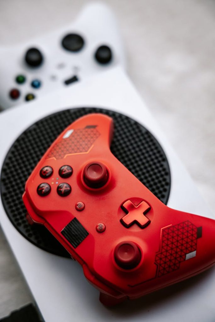 Close-up of a red Xbox wireless controller resting on a white gaming console, showcasing modern technology design.