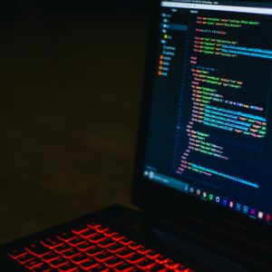Red backlit keyboard and code on laptop screen create a tech-focused ambiance.