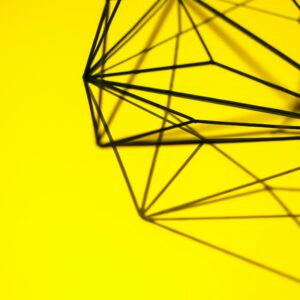 Creative geometric structure casting intricate shadows on a vibrant yellow background.